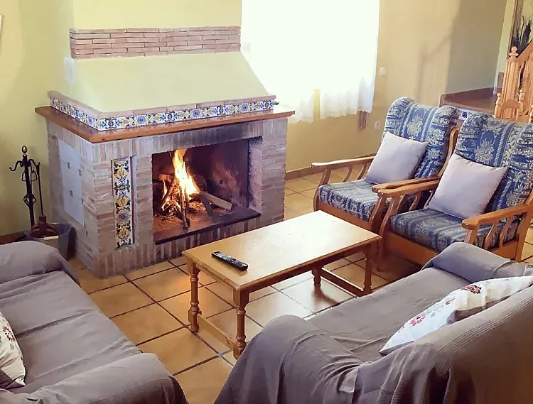 Salón con chimenea encendida en Fuente del Barrio